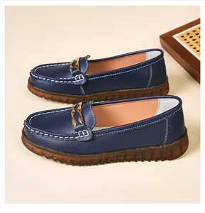 Dettaglio di raffinati mocassini in pelle blu navy con catena dorata e cuciture bianche