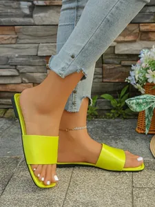 Ciabatte piatte verde lime da donna, mostrate mentre vengono indossate con dei jeans.