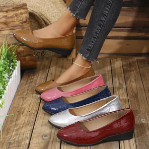 Detailed view of colorful women's crocodile embossed wedge shoes on rustic wood