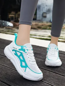 Detail van witte mesh hardloopschoenen met groenblauwe accenten en witte veters