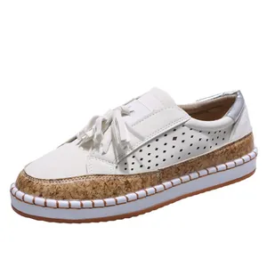 Vue détaillée de mocassins blancs avec pompons et bordure en texture de liège