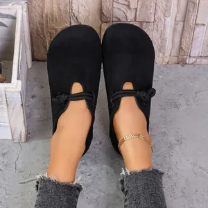 Vista superior de zapatos planos de ante negro con detalles de nudos únicos.