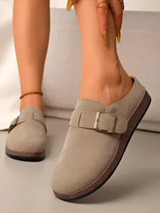 Close-up of vintage grey suede closed-toe mules featuring a stylish metallic buckle