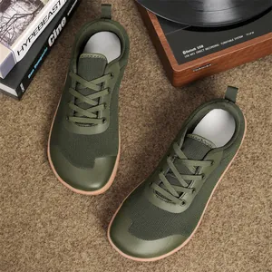 Top view of olive green wide-toe barefoot shoes on textured lifestyle background
