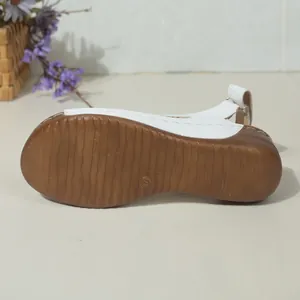 Detailopname van de bruine antislipzool met maatmerk op witte zomerse sleehaksandalen