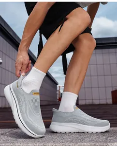 Detail view of grey breathable mesh slip-on walking shoes worn by a model outdoors.