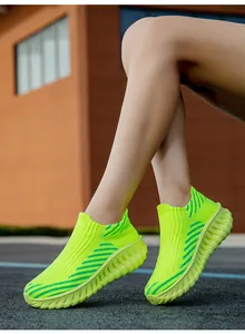 Close-up detailed view of neon green fly-knit slip-on sneakers worn by model outdoors
