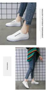 Μοντέλο που φοράει λευκά φλατ sneakers από συνθετικό δέρμα με στρογγυλή μύτη και κλασικό σχέδιο κορδονιών