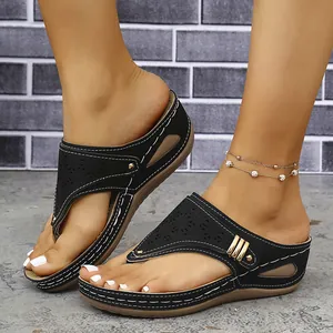 Primer plano de sandalias negras de cuña con puntera y patrones láser