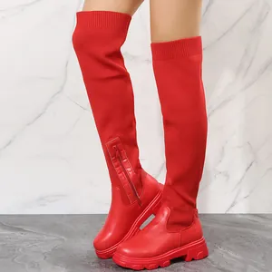 Macro detail shot of women's red over-the-knee boots featuring thick lug soles and knit fabric.