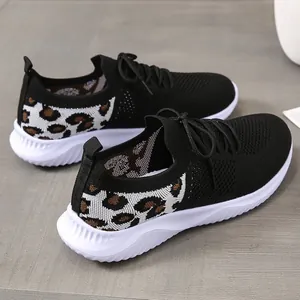 Close-up of women's black mesh sneakers featuring stylish leopard print and wavy white soles