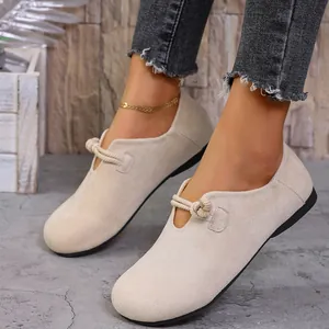 Primer plano de mocasines de ante beige para mujer con un detalle de nudo decorativo.
