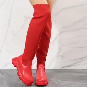 Close-up of vibrant red fly-knit thigh-high boots with chunky platform soles.