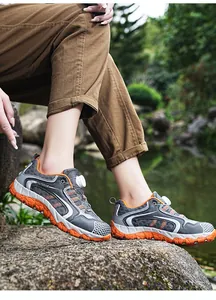 Nahaufnahme grauer und oranger Damen-Wanderschuhe mit Drehverschluss in der Natur.