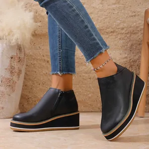 Vue latérale détaillée de bottines compensées noires élégantes avec fermeture éclair latérale.