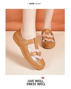 Detail of brown women's flat sandals featuring a pink heart woven design on foot.