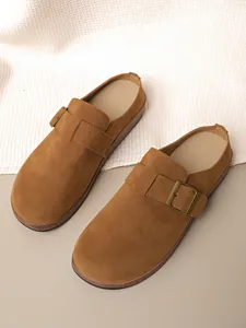 Detailed view of brown suede closed-toe mules with antique metal buckle strap