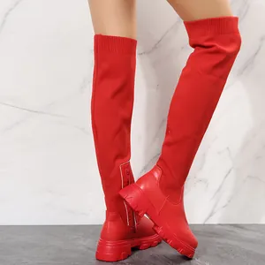 Detail of bright red fly-woven over-the-knee boots featuring chunky platform soles on a model.