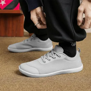 Detail shot of grey breathable flyknit wide-toe barefoot sneakers worn by a male model