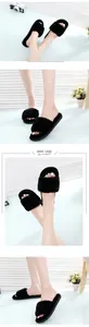 Close-up detail of black faux fur slippers showing soft texture and open-toe design