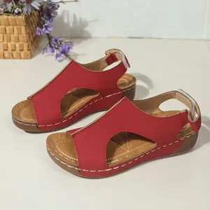 Close-up van rode sleehaksandalen met uitgesneden ontwerp en witte contraststiksels
