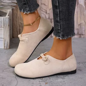 Primer plano de elegantes manoletinas de gamuza beige para mujer con detalle de nudo