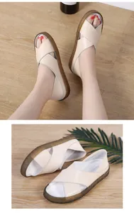 Detail view of cream women's cross strap wedge sandals on a textured wooden background