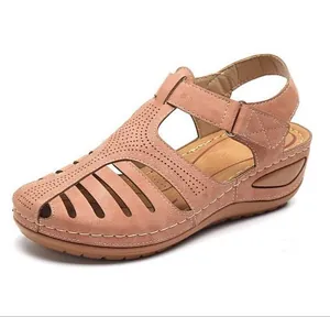 Side view of women's vintage closed-toe wedge sandals in pink with hollow-out design