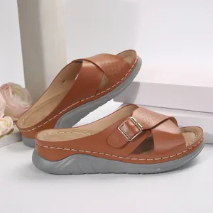 Macro detail view of brown women's casual cross strap platform sandals with golden buckle