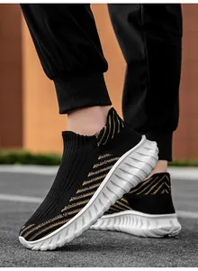 Detail view of black flying woven slip-on sports shoes with golden stripes and white sole.