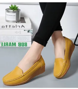 Detailansicht von gelben Leder-Loafers mit Keilabsatz und Kontrastnähten am Fuß.