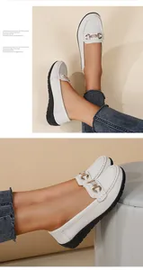 Detail view of stylish white women's loafers featuring elegant interlocking gold buckle