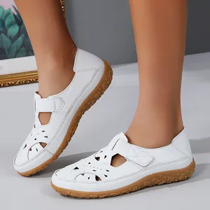 Detailed view of white hollowed-out flat sandals for women featuring floral textured rubber sole