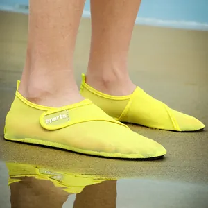 Detail of yellow mesh quick-dry beach shoes worn on sand with sports strap