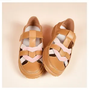 Close-up of comfortable tan women's flat sandals with pink heart woven straps.