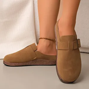 Detail of brown suede closed-toe mules with retro belt buckle and cork sole