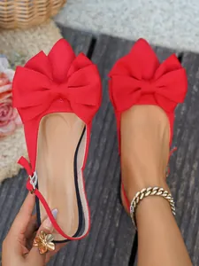 Gedetailleerde weergave van elegante rode platte sandalen met een grote stoffen strik