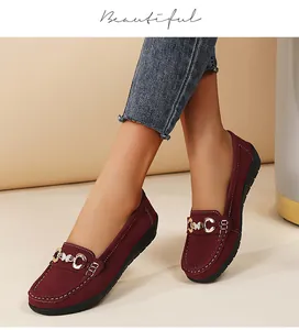 Detailed view of burgundy suede-like loafers with gold buckle and white stitching