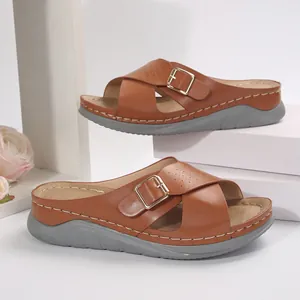 Side detail of tan women's platform slippers with cross straps and metallic buckle