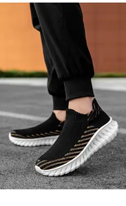 Comfortable black and gold fly-knit slip-on sneakers with thick white textured sole