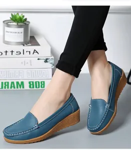 Nahaufnahme eleganter blauer Keilslipper aus Leder mit weißen Ziernähten für Damen