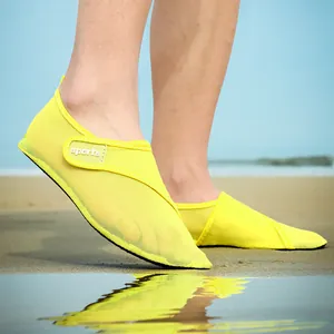 Detailed view of bright yellow mesh water shoes worn on a sandy beach for swimming