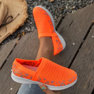 Detailweergave van oranje mesh sneakers met luipaardprint op een houten vlonderdek