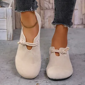 Primer plano de mocasines de ante beige con nudo decorativo de cuerda y punta redonda