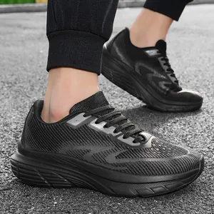Close-up of men's black breathable wide-toe mesh running shoes on asphalt pavement.