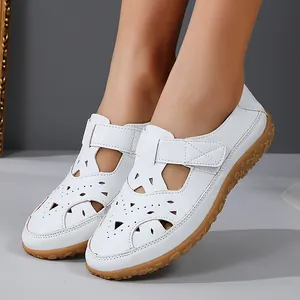 Detailed macro view of white women's breathable hollow-out leather flat sandals on feet