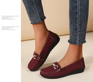 Detailed macro view of maroon suede loafers with stylish metal buckle on feet wearing jeans