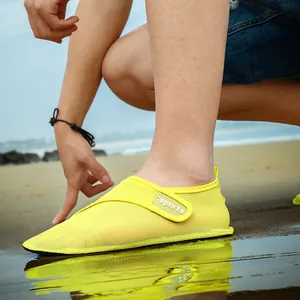 Detailed close-up of yellow mesh beach shoes with sports logo strap on a sandy sunny beach