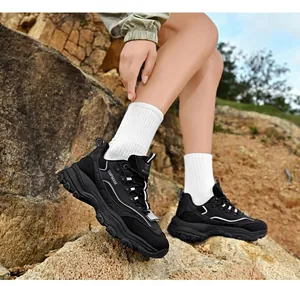 Detailed view of black chunky vintage dad sneakers worn on rocky outdoor terrain