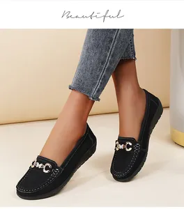 Detailed view of women's black flat loafers with gold buckle and contrast stitching.